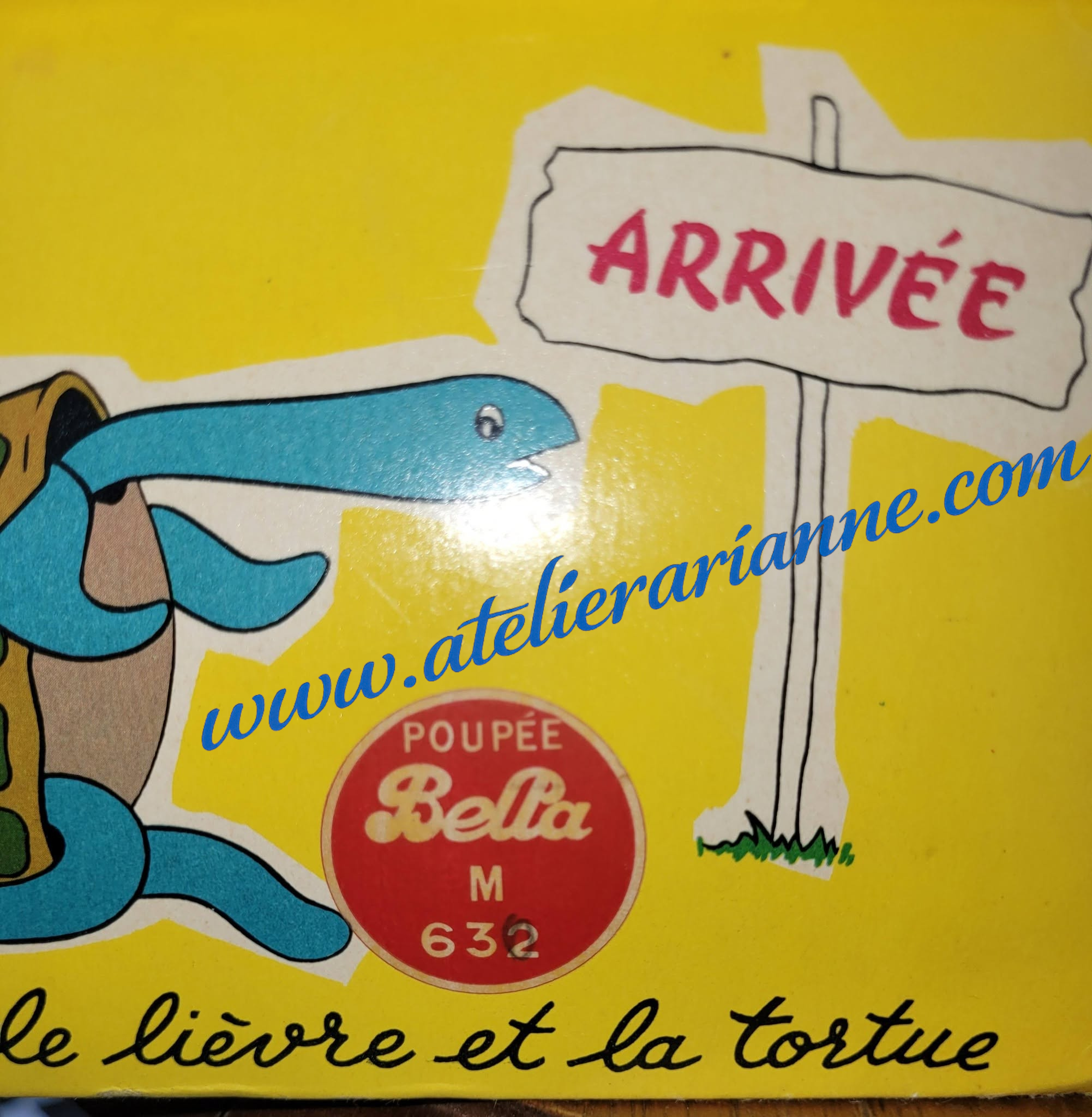 Bella M632 Christiane – grande poupée Bella des années 1960 — Détail de l’étiquette ronde rouge sur la boîte jaune de la poupée Bella M632 Christiane, indiquant « Poupée Bella M 632 », avec illustrations de l’emballage d’origine — vue 4.
