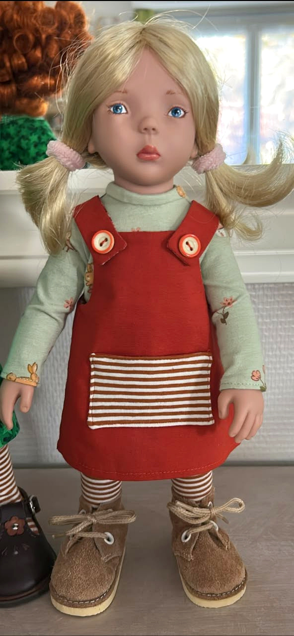 Trois Zwergnase en couleurs — collection de Dominique-Marie — Petite Zwergnase blonde de Dominique-Marie, avec deux couettes, une chasuble rouge brique à poche rayée, un haut vert pâle et des chaussures brunes à lacets — vue 2.
