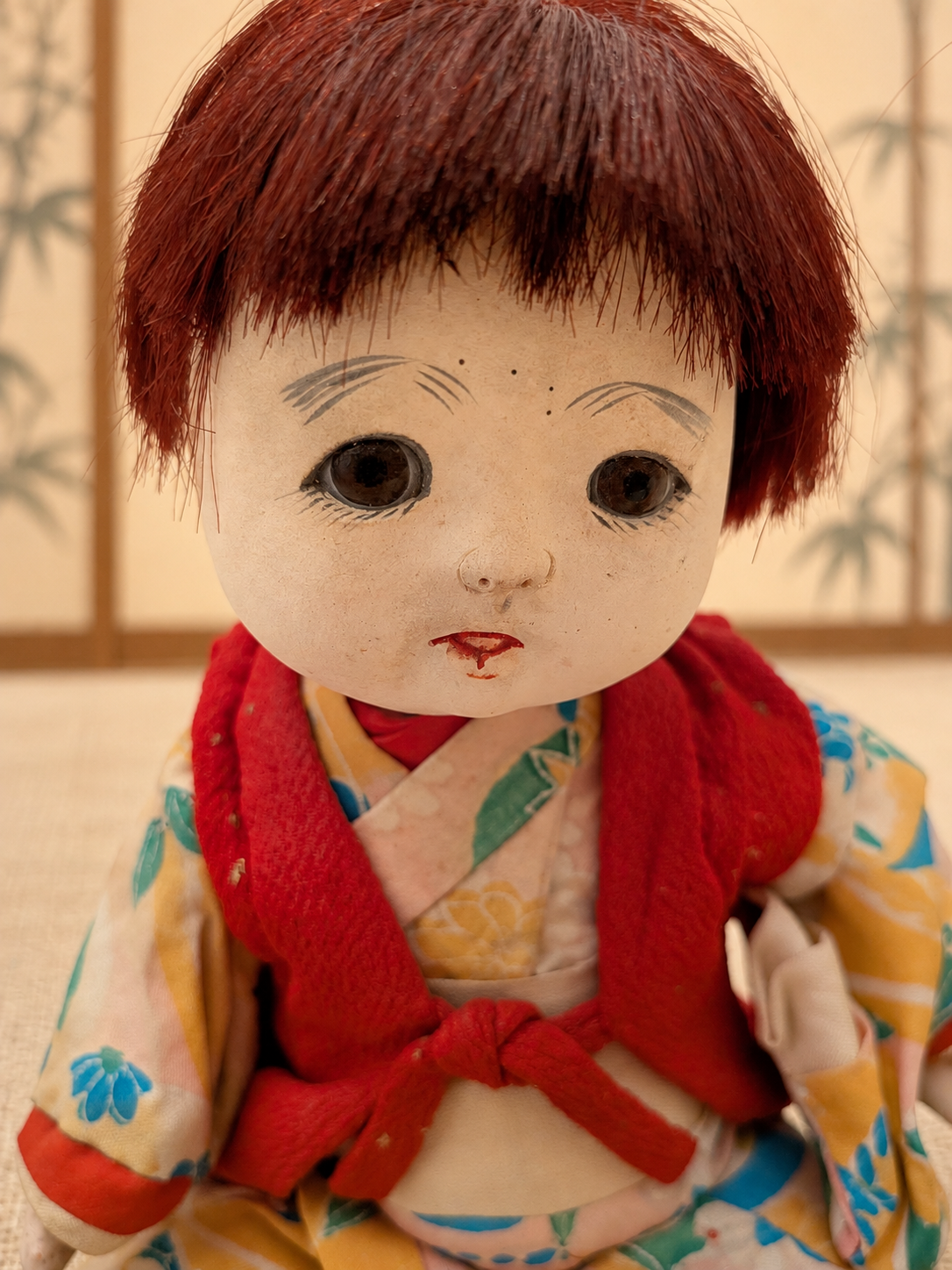 Deux poupées japonaises aux visages clairs — collection de Mireille — Portrait de la poupée en kimono : frange courte, yeux de verre selon Mireille et gilet rouge — vue 4.