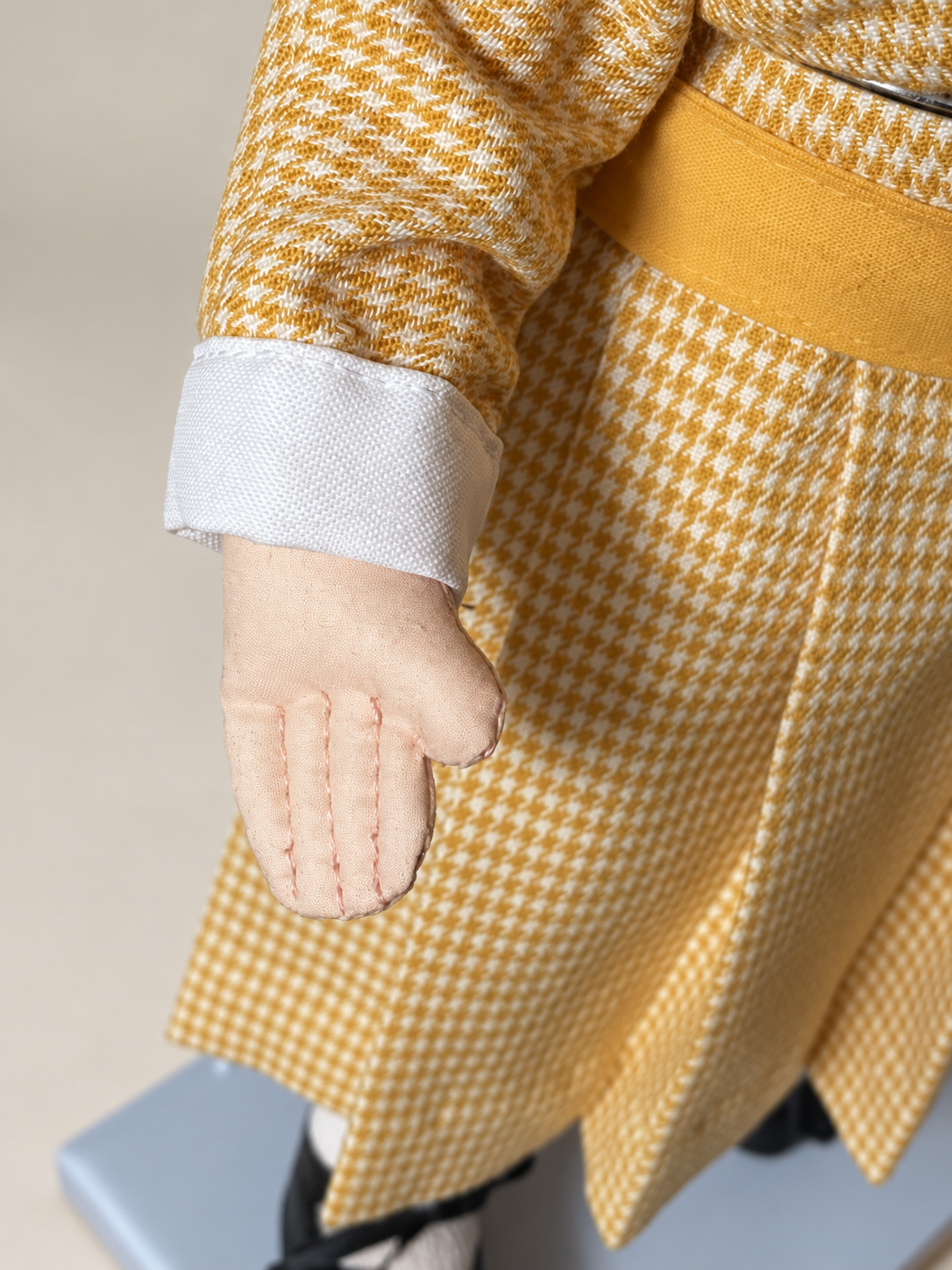 Une tête retrouvée, une poupée recréée — Femmes d’Aujourd’hui, collection de Françoise — Détail de la main en tissu cousue par Françoise, avec les coutures des doigts et le poignet blanc de la robe à carreaux ocre — vue 7.