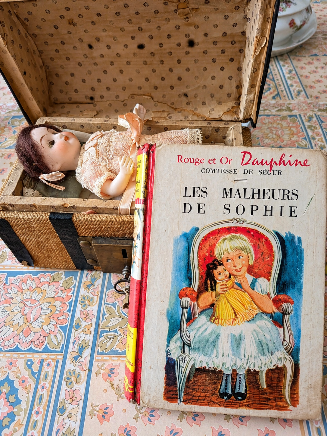 Mignonnette de 14 cm — mallette et trousseau — La poupée dans sa mallette, présentée avec le livre Les Malheurs de Sophie de la comtesse de Ségur — vue 2.