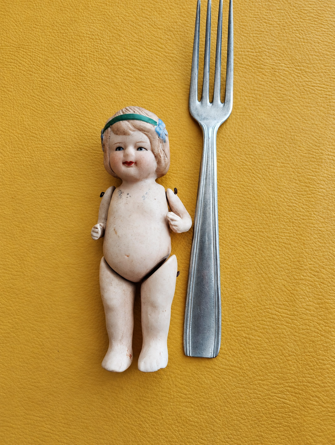 Petite poupée sans marque — trouvaille de Rose Louise — La poupée sans vêtements à côté d’une fourchette, montrant ses attaches et un repère visuel de taille — vue 2.