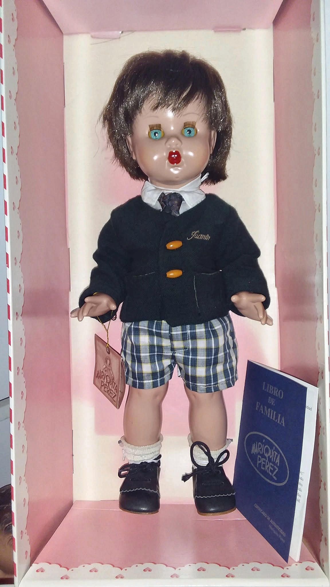 Juanín écolier en boîte — Mariquita Pérez, collection de Vincente — Juanín écolier de Mariquita Pérez en boîte d’origine rose, portant sa tenue d’origine : veste bleu marine brodée Juanin, chemise blanche, cravate, short à carreaux, chaussettes claires et chaussures à lacets ; étiquette et Libro de familia visibles — vue 1.