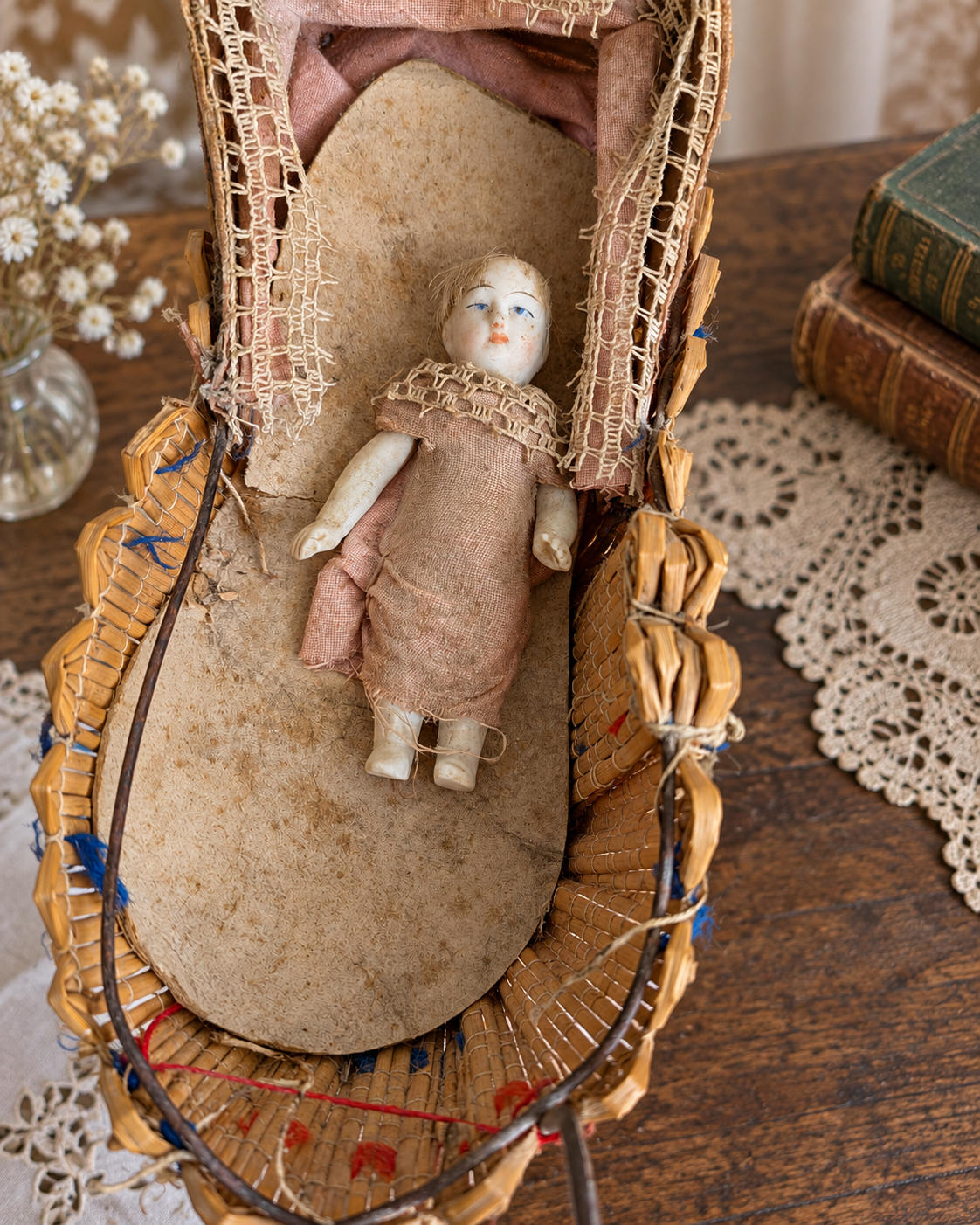 Mignonnettes anciennes et leurs petits accessoires — collection de Mireille (1/3) — Petite poupée dans un berceau tressé, avec sa garniture textile usée et ses dentelles — vue 2.