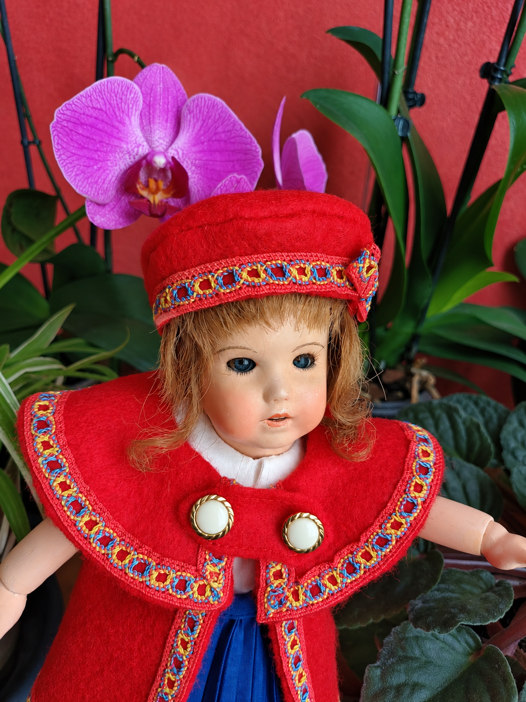 Bleuette 251 — la nouvelle tenue rouge et bleue cousue par Françoise — Détail du large col rouge, des deux boutons clairs cerclés de doré et du galon multicolore de la tenue cousue par Françoise — vue 2.