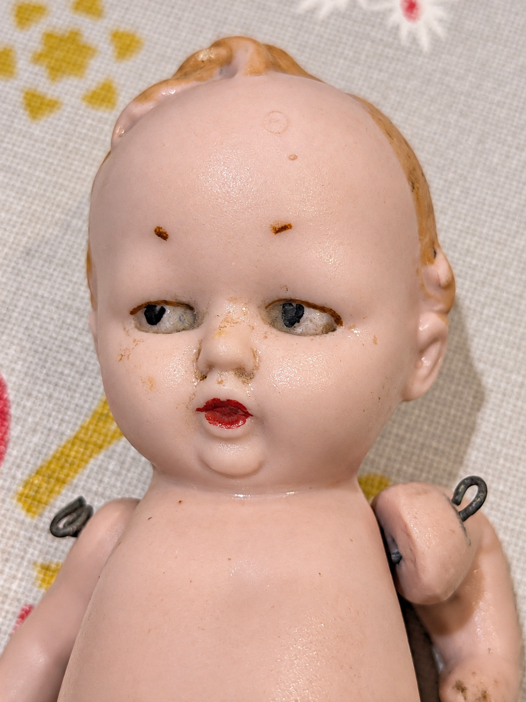 Bébé humoristique tout en porcelaine — collection de Mireille — Portrait de face : yeux peints, bouche rouge et coiffure figurée en relief — vue 2.
