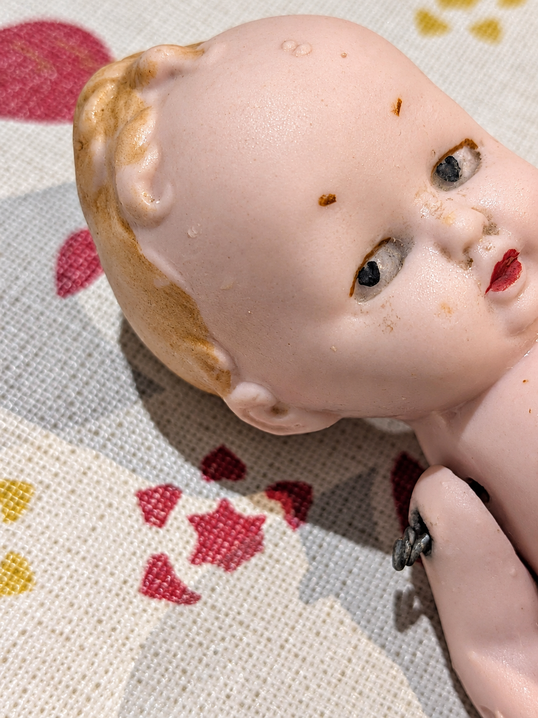Bébé humoristique tout en porcelaine — collection de Mireille — Portrait rapproché incliné montrant la petite mèche et l’attache d’un bras — vue 3.